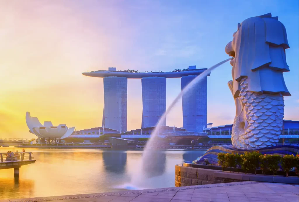 Iconic view of Singapore's Merlion Park with the Merlion statue in the foreground, Marina Bay Sands hotel and ArtScience Museum in the background, at sunrise