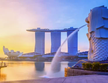 Iconic view of Singapore's Merlion Park with the Merlion statue in the foreground, Marina Bay Sands hotel and ArtScience Museum in the background, at sunrise