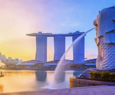 Iconic view of Singapore's Merlion Park with the Merlion statue in the foreground, Marina Bay Sands hotel and ArtScience Museum in the background, at sunrise