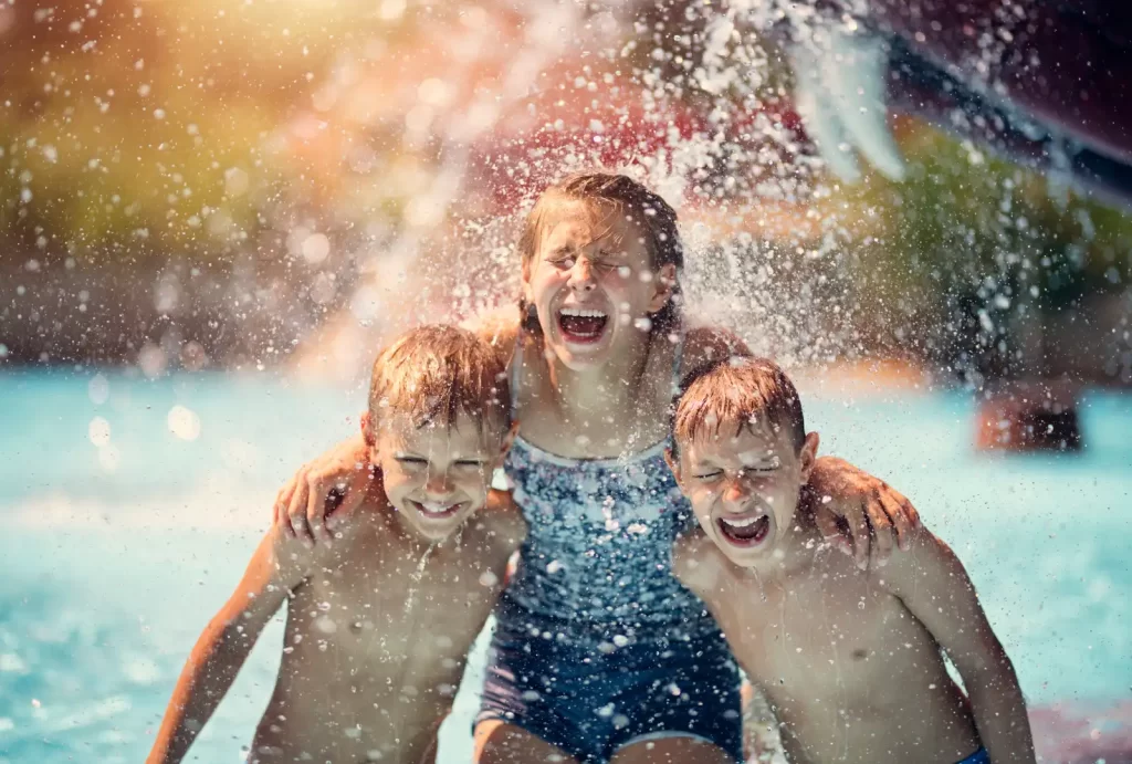 Three joyful children splashing and playing together at a vibrant water park, enjoying a sunny day of fun.