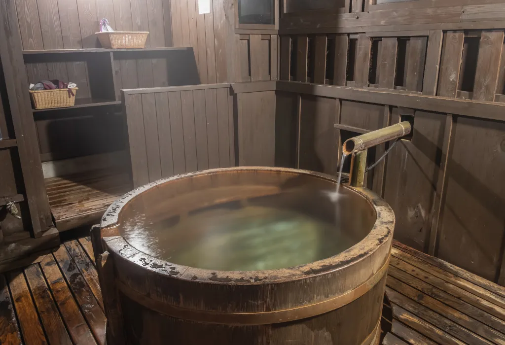 Traditional indoor onsen hot spring in a wooden tub (ofuro), offering a private and authentic Japanese bath experience. A highlight of luxury Japan holidays and Japan travel at a classic ryokan, arranged by a Japan dmc.