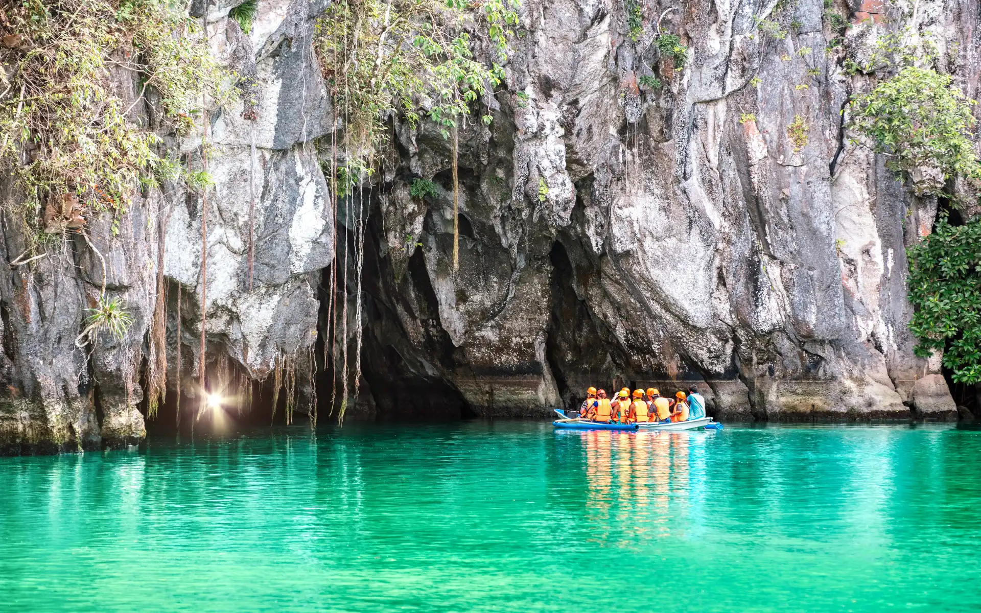 Tourists in a boat exploring the entry of the Puerto Princesa Underground River in Palawan, a top UNESCO eco-adventure destination for corporate groups.