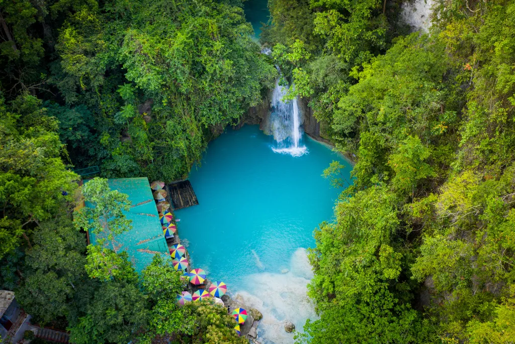 Panoramic aerial view of Kawasan Falls, a stunning natural paradise in Cebu, offering a picturesque setting for luxury travel, team-building, and MICE events amidst lush greenery.