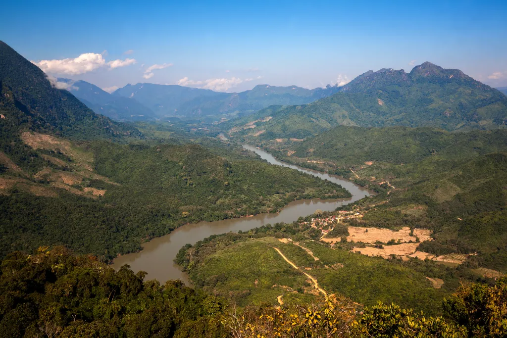 Expansive view of a winding river through a verdant Laotian valley with distant mountains, representing opportunities for unique expeditions and incentive travel programs.