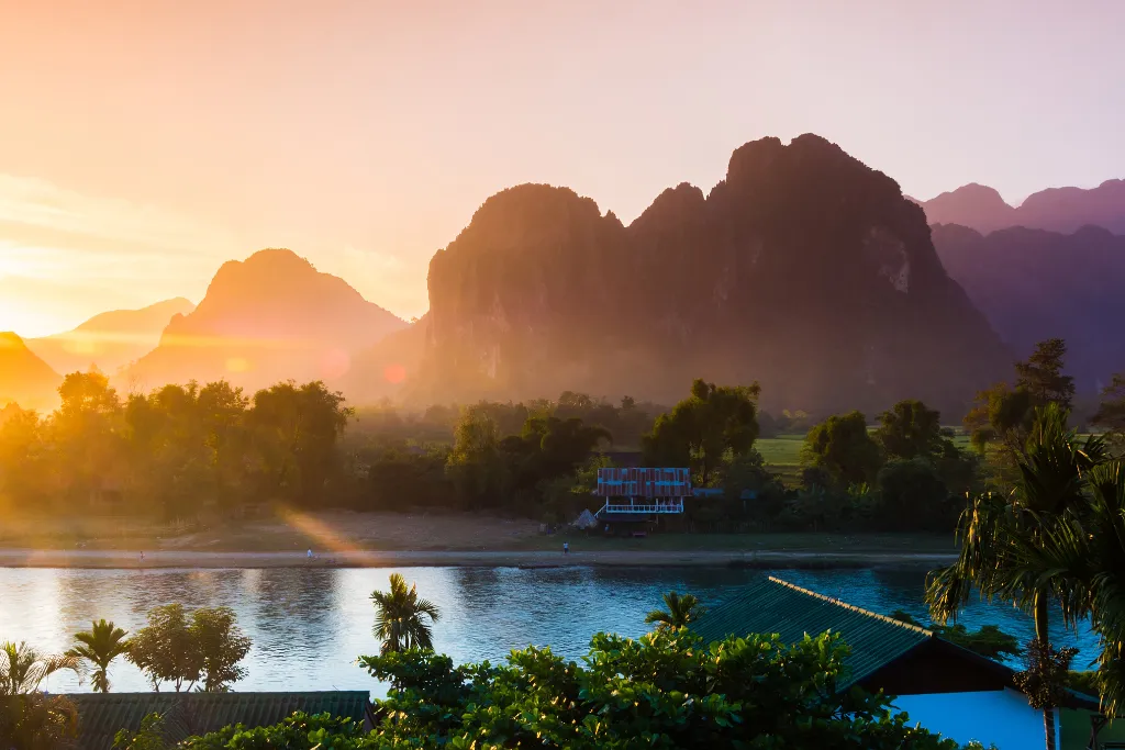 Breathtaking sunset over limestone karst mountains and river in Laos, offering a serene backdrop for luxury travel and exclusive events.
