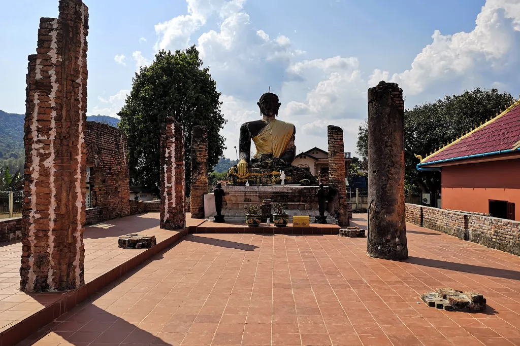 Serene Buddha statue amidst ancient temple ruins in Phonsavan, Laos, offering a spiritual and historical encounter for luxury travelers and MICE/DMC programs.