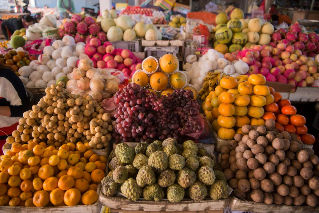 Vibrant display of fresh, colorful tropical fruits at a local market in Phonsavan, Laos, showcasing authentic culinary experiences for luxury travel groups.