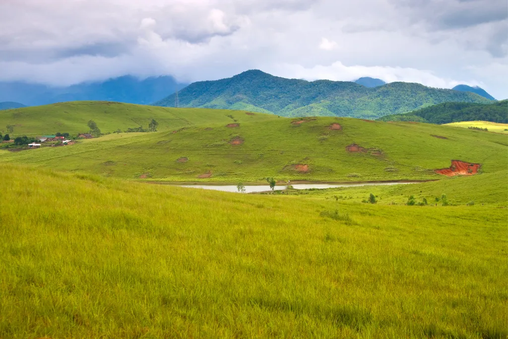 Expansive rolling green landscapes and a peaceful lake in Phonsavan, Laos, perfect for luxury nature retreats and DMC curated itineraries.