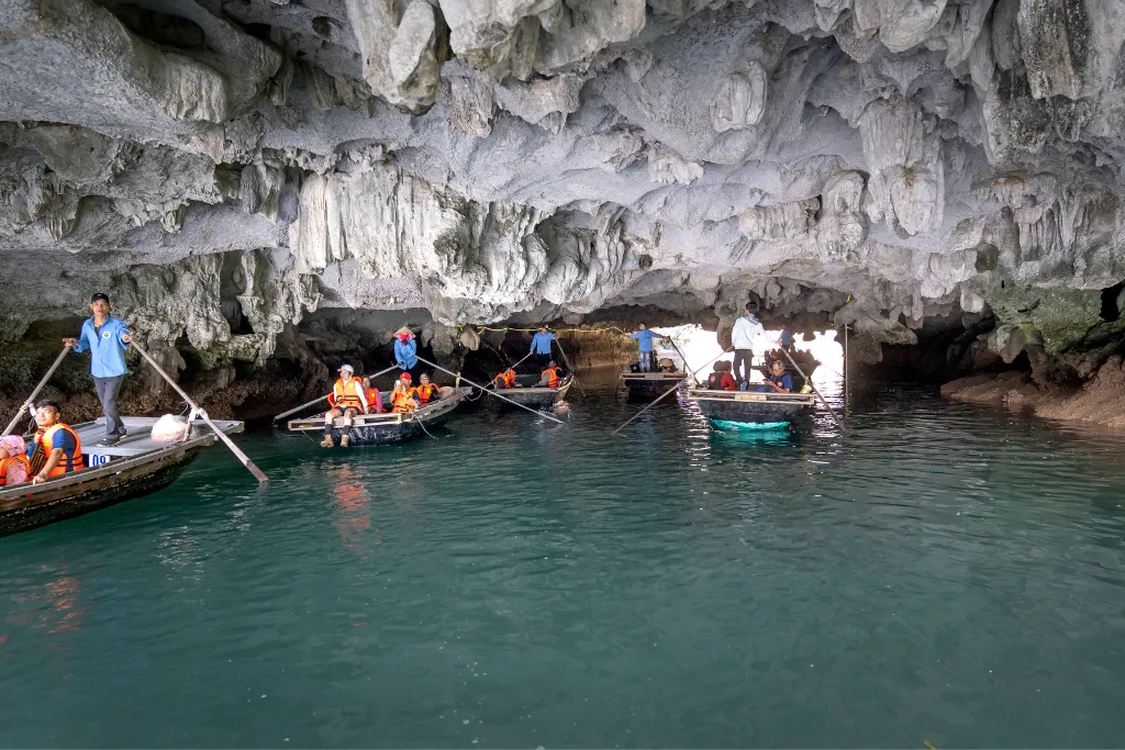 Exploring a stunning grotto in Ha Long Bay by rowboat, an immersive natural experience for luxury tours and unique DMC excursions.