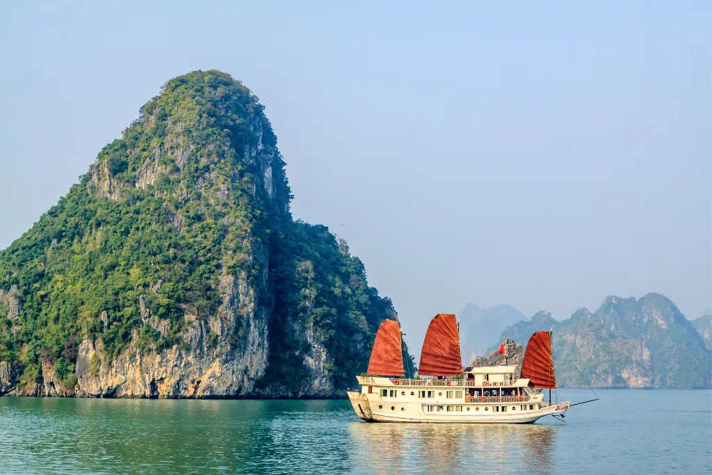 Elegant traditional junk boat cruising in Ha Long Bay, showcasing iconic Vietnamese beauty for discerning luxury travelers and exclusive MICE groups.