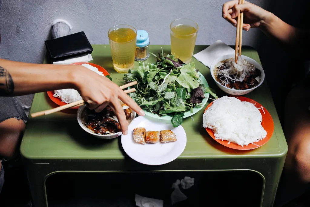 Authentic Vietnamese street food, Bun Cha, being enjoyed by travelers, highlighting the unique culinary experiences available for luxury and DMC clients in Hanoi.