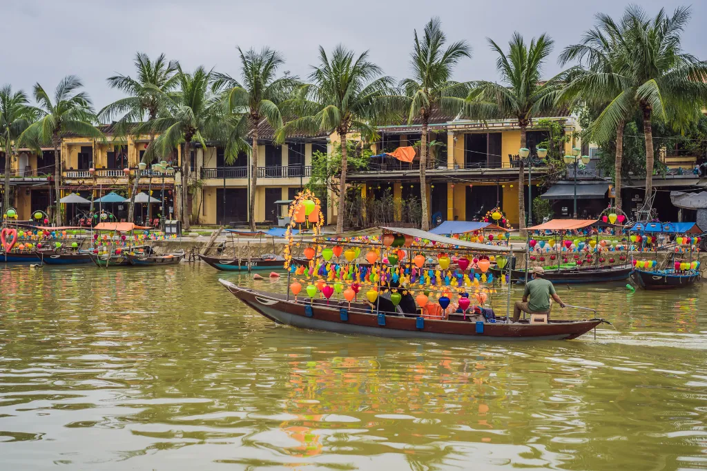Colorful lantern boats on the Thu Bon River in Hoi An, an idyllic setting for an exclusive MICE incentive travel experience or luxury leisure tour.