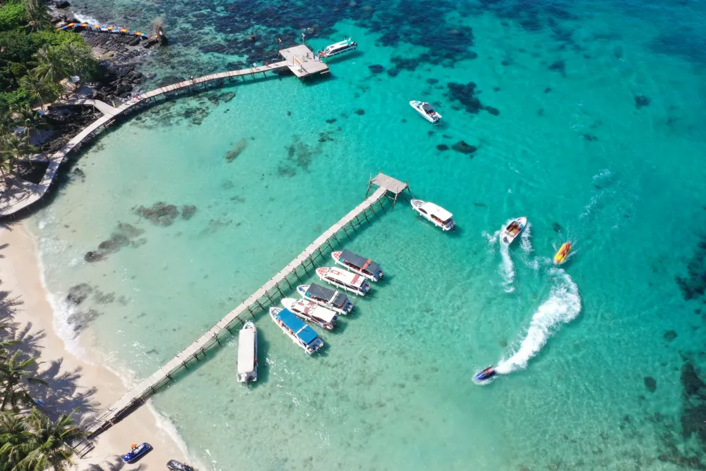 Aerial view of a picturesque private pier extending into the dazzling clear blue waters of Phu Quoc, surrounded by luxury boats, ideal for exclusive excursions and DMC-arranged activities.