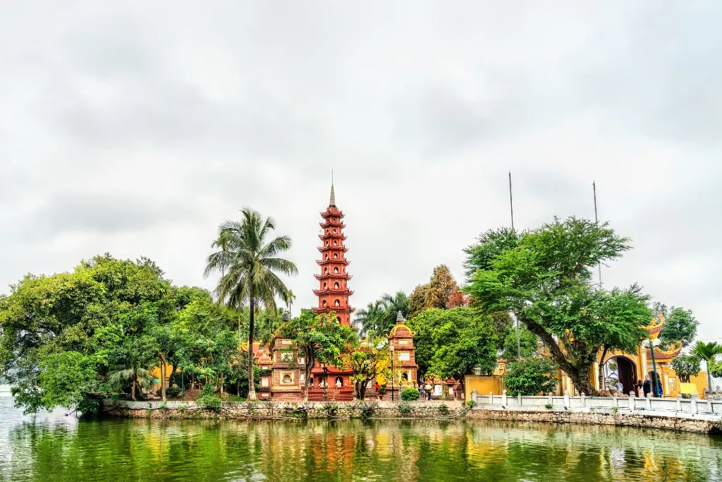 The picturesque Tran Quoc Pagoda on West Lake in Hanoi, surrounded by lush greenery, offering serene views for luxury travelers and MICE groups.
