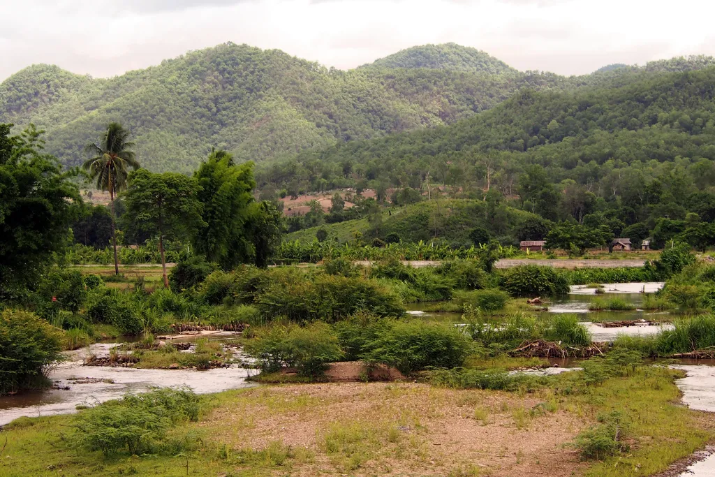 A tranquil river flows through the lush, mountainous landscape of Pai, Thailand, showcasing the region's natural beauty. An ideal destination for a luxury escape or a DMC-curated itinerary.