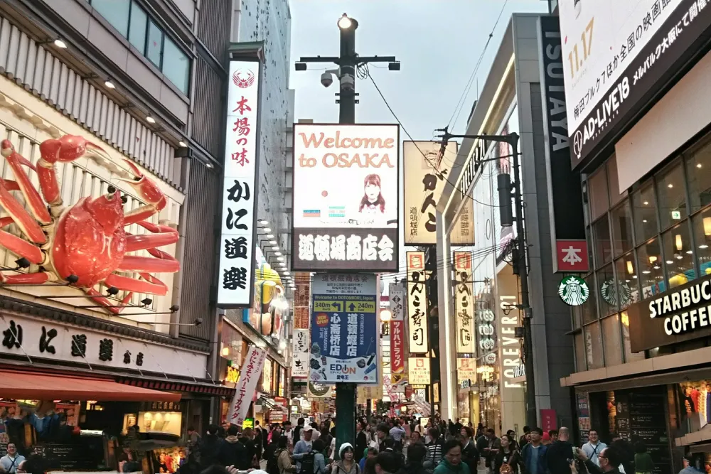 A bustling view of the vibrant Shinsaibashi shopping street in Osaka at night, with towering billboards and a lively crowd. This urban scene is a great example of the exciting nightlife and exploration experiences a Japan DMC can arrange for MICE groups.
