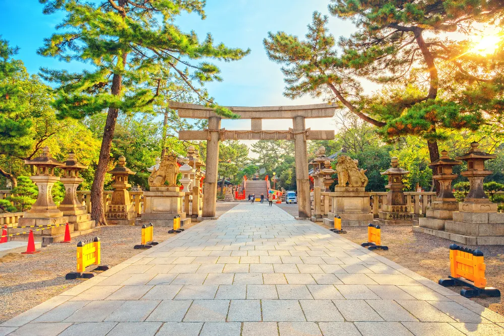 The main torii gate and stone lanterns of Sumiyoshi Taisha (Sumiyoshi Grand Shrine) in Osaka are illuminated by the sun. This historic and spiritual site is a powerful cultural landmark for luxury travel and MICE groups.