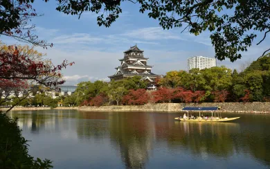 Hiroshima Castle reflected in the calm waters of its moat, surrounded by vibrant autumn foliage. We craft unique itineraries for our corporate and MICE clients, providing unforgettable seasonal views and cultural immersion.