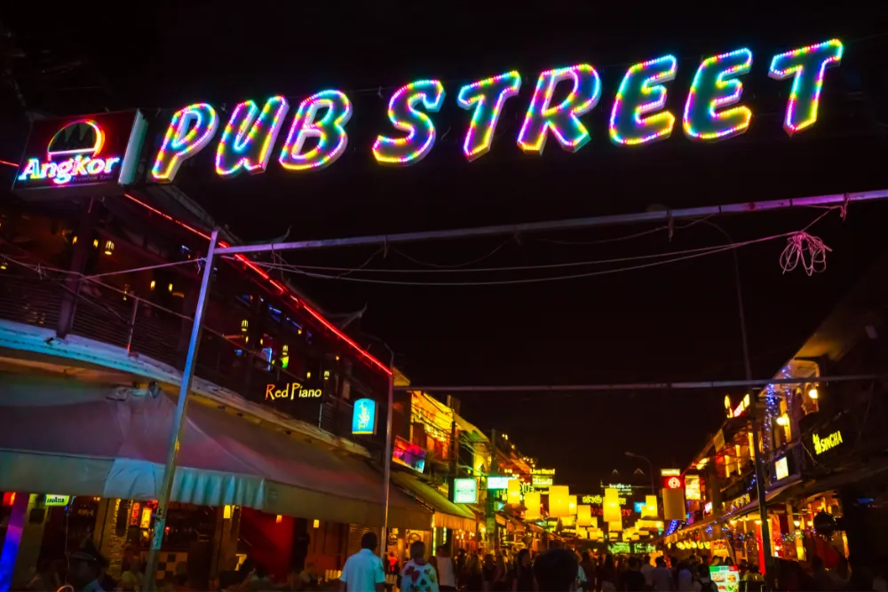 Vibrant nightlife on Pub Street in Siem Reap, Cambodia, featuring colorful neon lights and bustling restaurants.