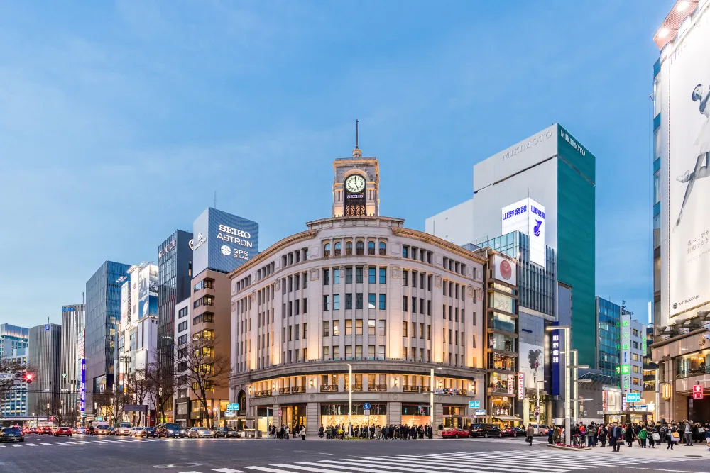 A nighttime view of the iconic Ginza shopping district in Tokyo with the historic Seiko clock tower. This image highlights the high-end retail and luxury experiences of a tour in Japan.