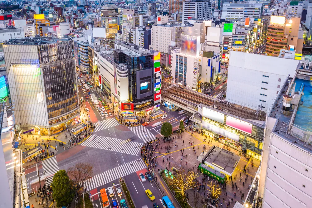 A high-angle view of the bustling Shibuya Crossing in Tokyo at dusk. This image highlights the city's modern atmosphere