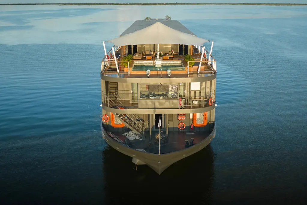 A modern, luxury Mekong River cruise ship sailing under clear skies, offering premium Vietnam and Cambodia tours.