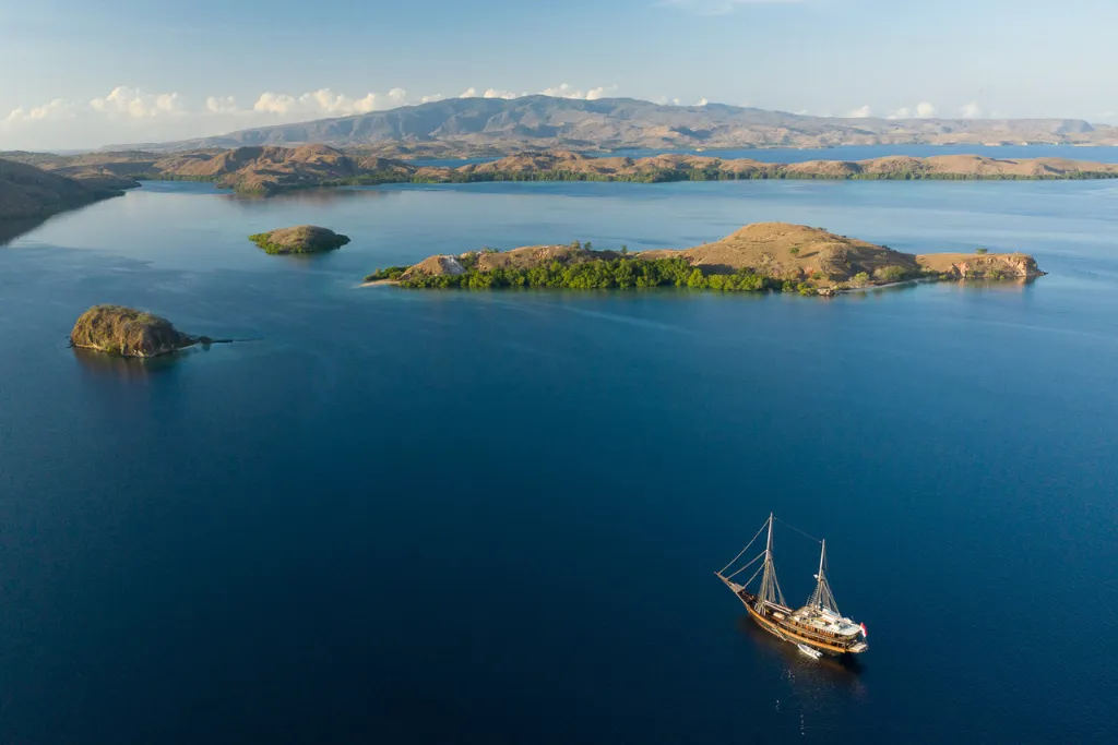 Luxury private Phinisi yacht cruising the clear blue waters of Komodo National Park, a highlight of exclusive Indonesia DMC and Indonesia tours. Experience bespoke Indonesia travel and unforgettable Indonesia holidays with a private charter.