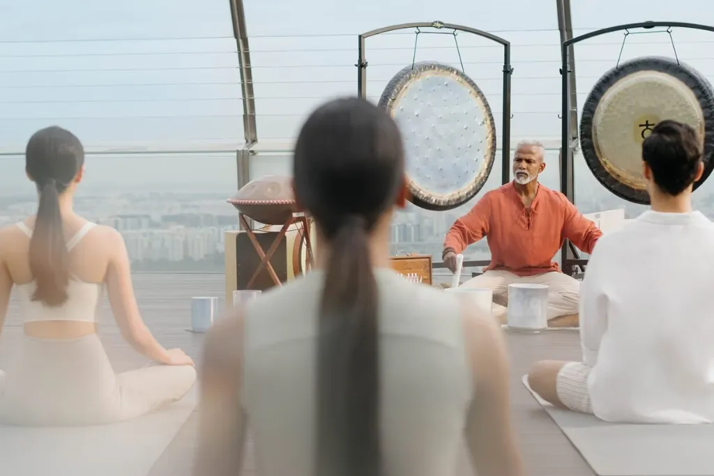 Guests participating in an exclusive rooftop sound bath or wellness class with gongs.