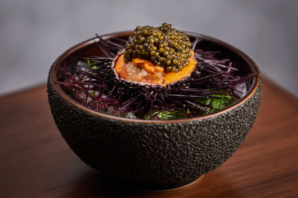 Close-up of a luxurious dish featuring sea urchin (uni) topped with caviar and fine herbs. Experience the best fine dining in Singapore and Malaysia on our luxury tours.