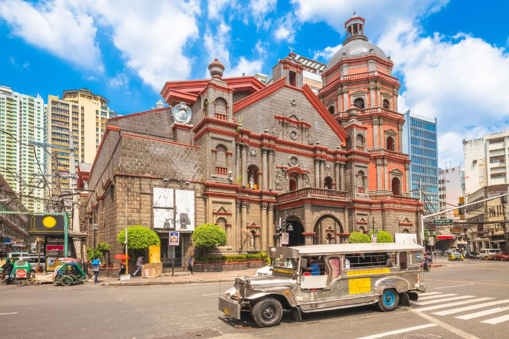 Historical church landmark and a traditional Jeepney in the bustling city of Manila, Philippines. Explore cultural heritage and exciting Manila city tours on your Philippines travel package.