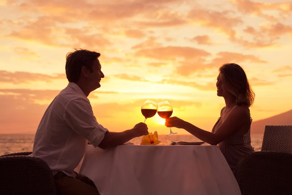 Couple enjoying a romantic sunset dinner on the beach with wine toast. Highlight for luxury Japan holidays and honeymoon Japan travel packages arranged by a specialized Japan dmc.