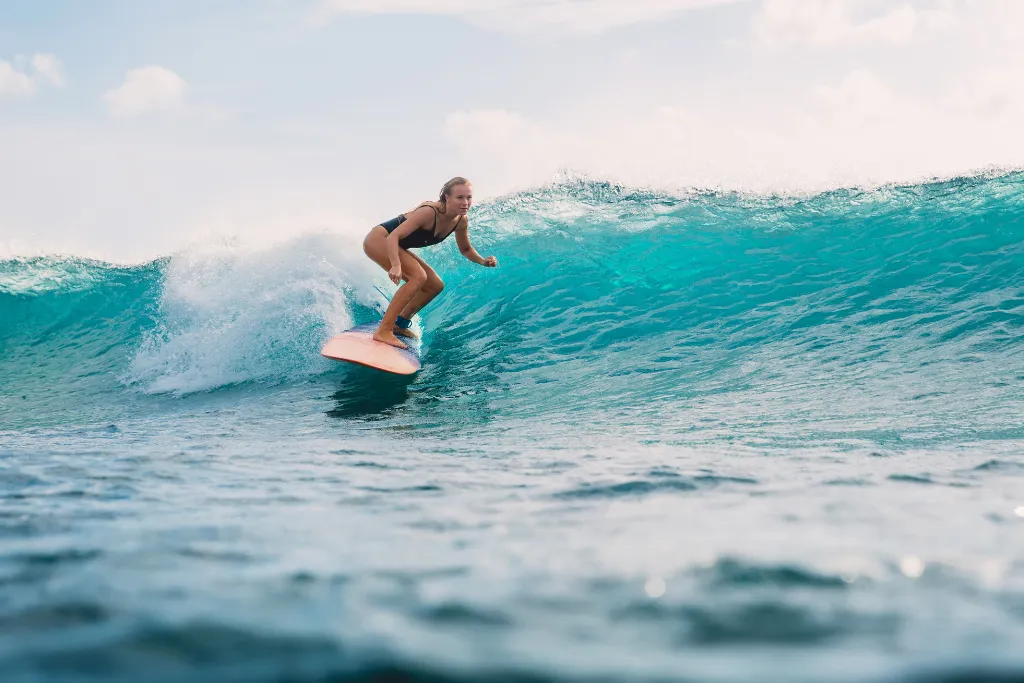 Surfer riding a turquoise wave, representing the excellent surfing and water sports available in the Philippines, perfect for adventure holidays and Siargao travel tours.