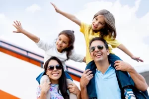 Smiling family of four (parents with children on their shoulders) enjoying a luxury travel vacation planned by a premium travel agency.