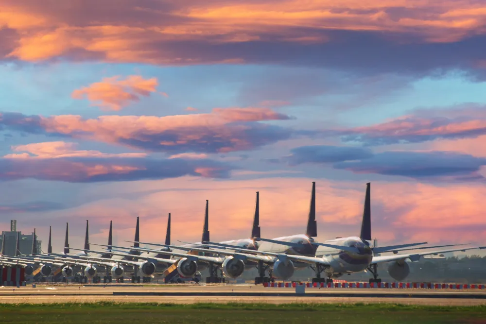 Passenger aircraft lined up at Bangkok's airport at sunset