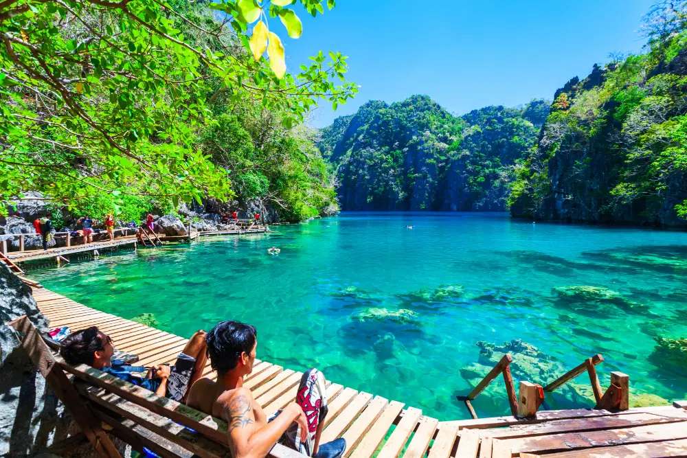 Travelers relaxing on the wooden boardwalk at Kayangan Lake in Coron, Palawan during a guided island-hopping tour with Discovery DMC.