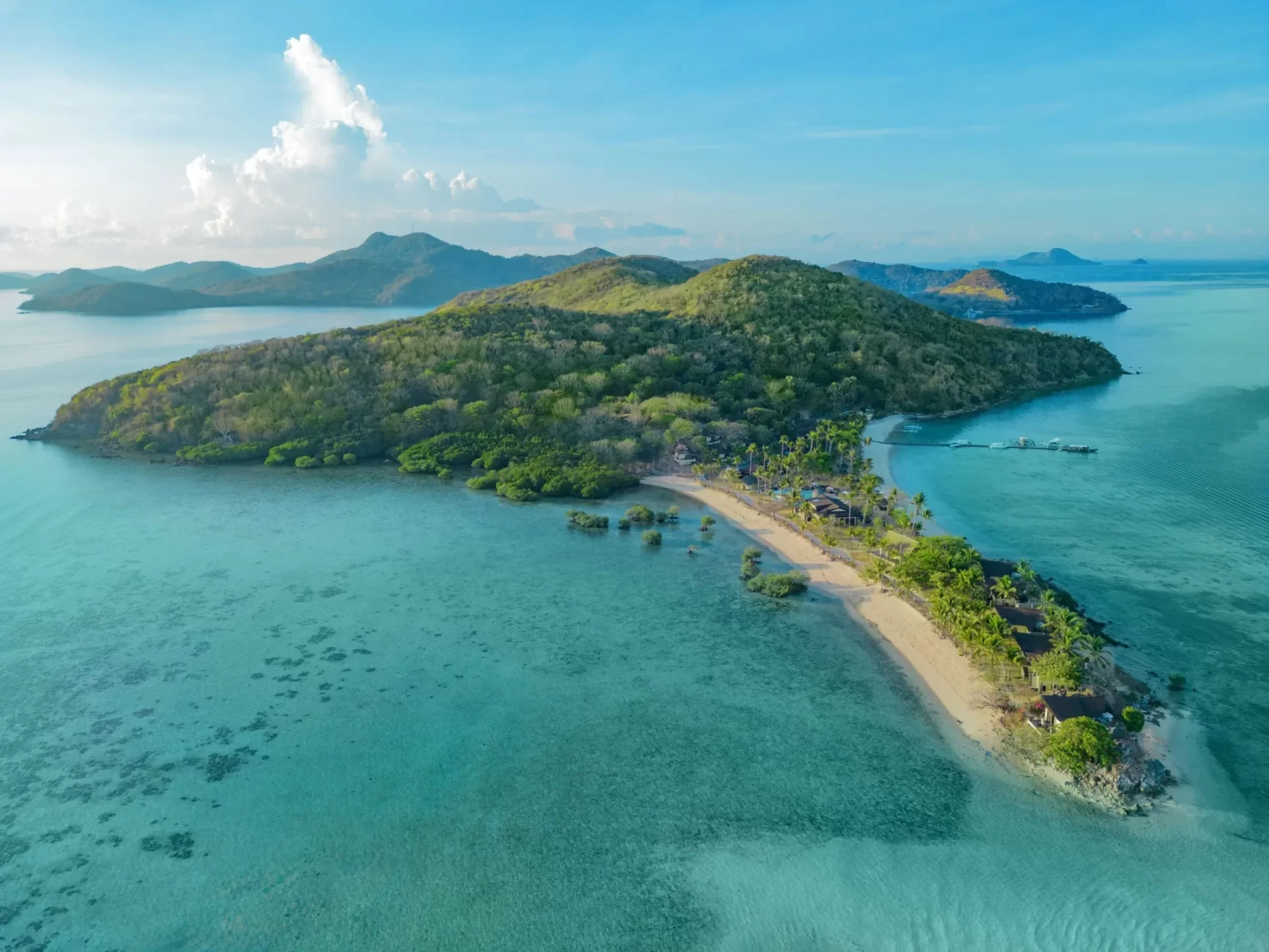 Aerial view of a luxury beach resort on a tropical private island surrounded by clear turquoise waters, curated by Discovery DMC.