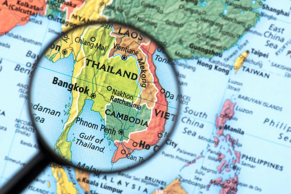 Map of Thailand highlighted with a magnifying glass, showing Bangkok, Chiang Mai, and the surrounding Mekong region including Laos, Cambodia, and Vietnam