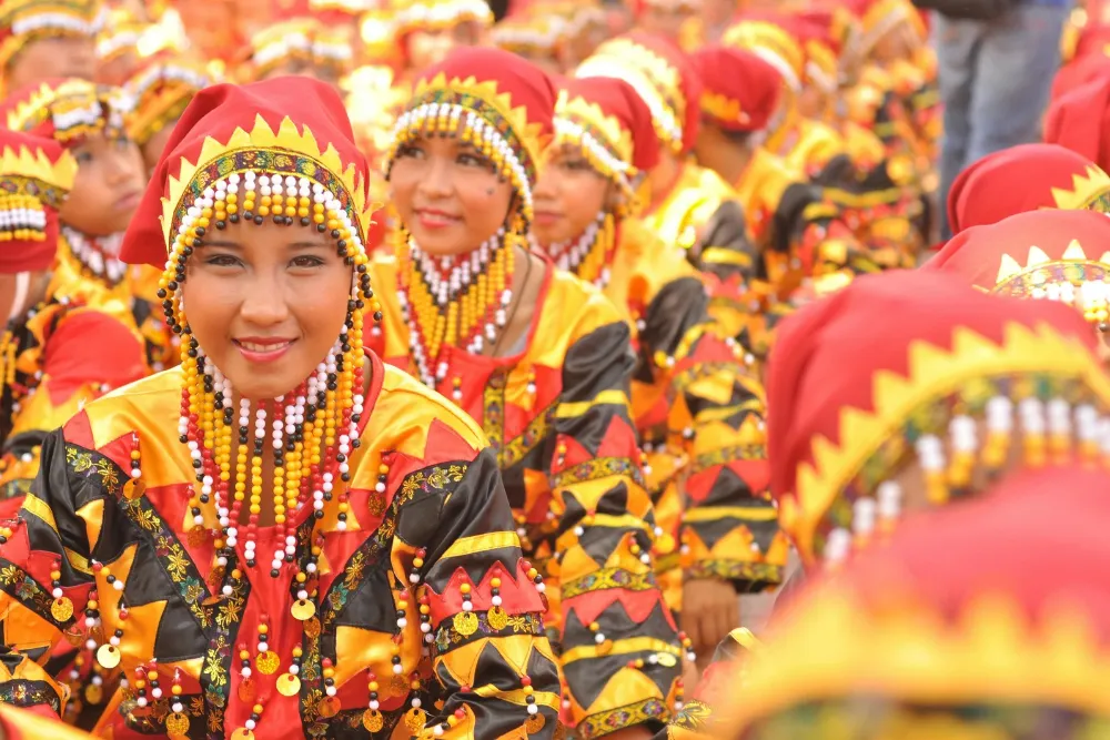 women wearing beaded headpieces and traditional red and yellow attire during a cultural festival on a Philippines tour.
