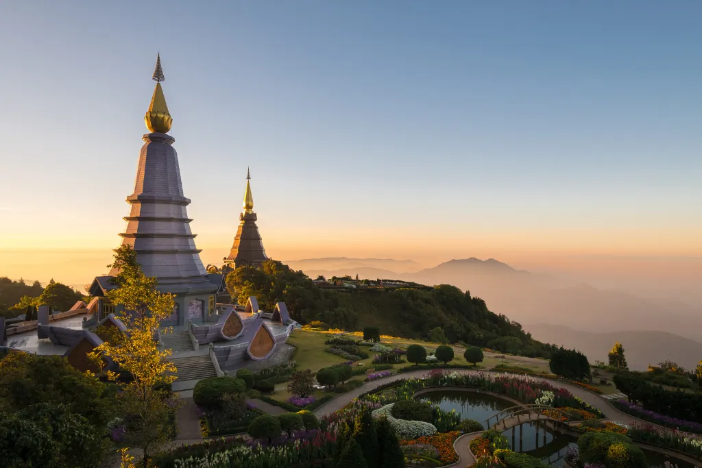 Twin Royal Pagodas surrounded by flower gardens at Doi Inthanon during sunset, featured in North Thailand tours by a local Thailand DMC.