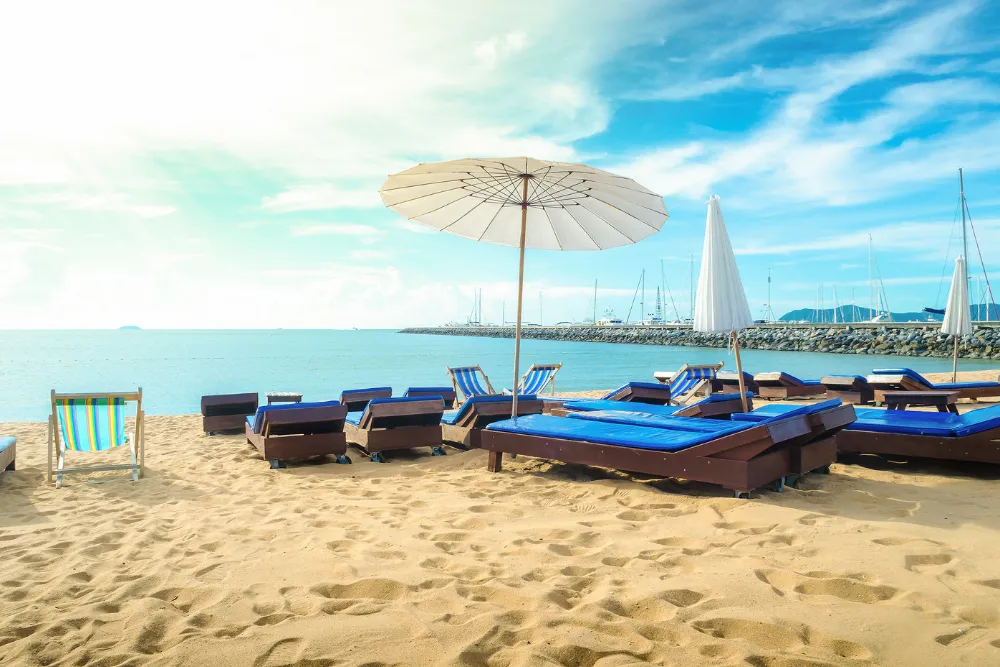 Relaxing beach loungers and sun umbrellas on a sandy beach, managed by a premier Thailand DMC for luxury island getaways.